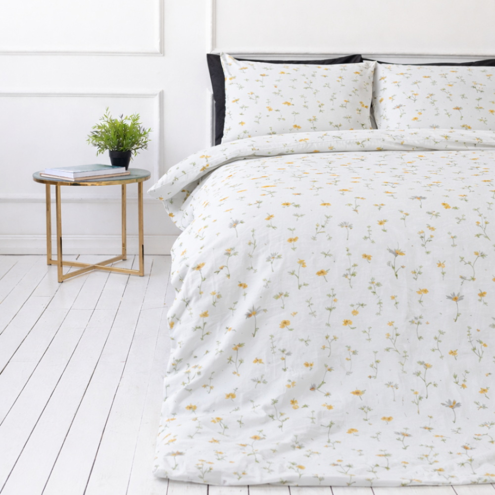 Pussilakanasetti „Enigma“. Kuvioitu pussilakanasetti, 100x140 cm, 140x200 cm, 150x210 cm, 160x200 cm, 180x200 cm, 200x200 cm, 200x220 cm, 230x220 cm. Elegantti valkoinen vuodevaatesetti valkoisella pohjalla, jossa on hienovaraisia keltaisia päivänkakkaroita ja pehmeitä vihreitä varsia.