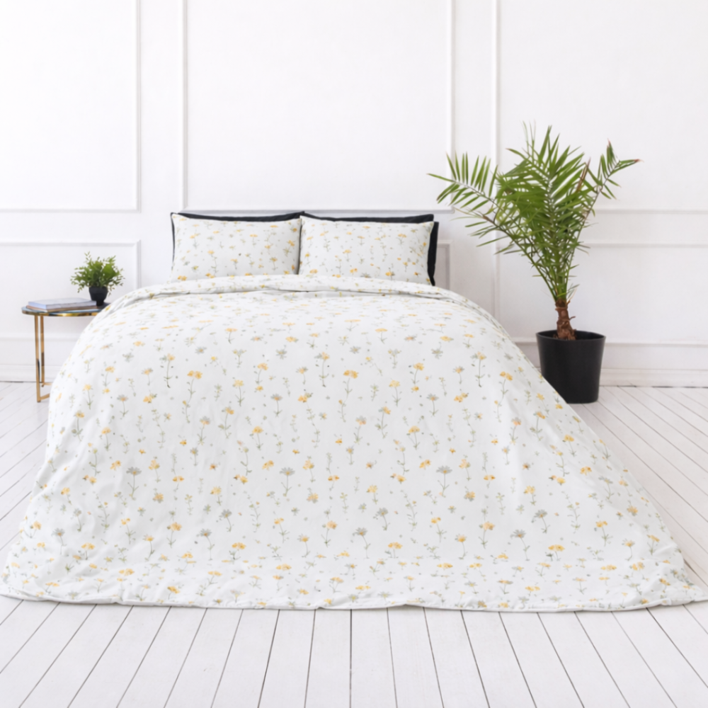 Pussilakanasetti „Enigma“. Kuvioitu pussilakanasetti, 100x140 cm, 140x200 cm, 150x210 cm, 160x200 cm, 180x200 cm, 200x200 cm, 200x220 cm, 230x220 cm. Pehmeä valkoinen vuodevaatesetti romanttisella pienimuotoisella kuviolla keltaisista kukista ja vihreistä kasveista.